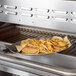 An oval aluminum sizzler platter filled with chips on a grill.