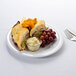 A Thunder Group white melamine plate with a sandwich and grapes on it.