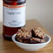 A bowl of chocolate covered toffee with nuts next to a bottle of LorAnn Oils English Toffee flavor.