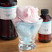 A bowl of cotton candy with a bottle of LorAnn Cotton Candy flavor on the counter.