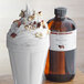 A glass of chocolate milkshake with nuts and a bottle of LorAnn Oils Creamy Hazelnut syrup.