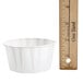 A Solo 5.5 oz. paper souffle cup next to a ruler.