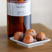 A plate of chocolate truffles with a bottle of LorAnn Oils All-Natural Citrus Blossom Flavor on the counter.