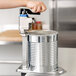 A hand uses a Vollrath Redco EaziClean heavy duty can opener on a counter.