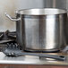 A black Thunder Group pasta fork in a large metal pot on a stove.