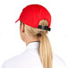 A woman wearing a red Headsweats 5-panel cap with a ponytail.