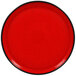 A red porcelain plate with a black rim.