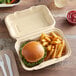 A Fabri-Kal Greenware hinged container with a burger and fries inside.
