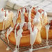 Cinnamon rolls with Rich's Classic White Donut & Roll Icing on a cooling rack.