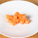 A plate of diced carrots with cubes of orange food on it.