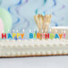 A birthday cake with white frosting and "Happy Birthday" candles on it.