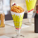 A Carnival King french fry cone filled with french fries on a table with a glass of beer.