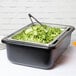 A Carlisle black cold food pan holder on a table with salad in it.