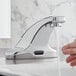 A hand washing under a Sloan deck mounted sensor faucet.