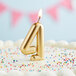 A gold number four candle on a white birthday cake.