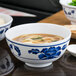 A close up of a white Thunder Group Lotus melamine bowl filled with noodles in soup.