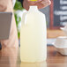 A person pouring lemonade into a translucent HDPE juice jug with a handle.