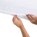 A person's hands holding a white Foundations SafeFit fitted sheet.