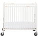 A white Foundations compact steel crib with slatted ends and wheels.
