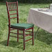 A Lancaster Table & Seating mahogany Chiavari chair with a green cushion on a table.