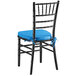 A Lancaster Table & Seating black wood chiavari chair with a blue cushion.