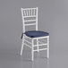 A white Lancaster Table & Seating Chiavari chair with a navy blue cushion.