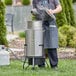 A man wearing an apron cooking outside with a Backyard Pro Seafood Boiler and Steamer Kit.