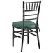 A Lancaster Table & Seating black wood chiavari chair with a green cushion.