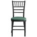 A Lancaster Table & Seating black wood chiavari chair with green cushion.