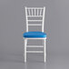 A white Lancaster Table & Seating Chiavari chair with blue cushion.