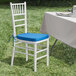 A Lancaster Table & Seating white wood Chiavari chair with blue cushion.