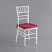 A white Lancaster Table & Seating Chiavari chair with a red cushion.