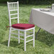 A Lancaster Table & Seating white wood Chiavari chair with a wine red cushion.