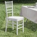 A white Lancaster Table & Seating Chiavari chair with white cushion sits in the grass.