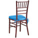 A Lancaster Table & Seating mahogany Chiavari chair with a blue cushion.