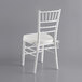 A white Lancaster Table & Seating Chiavari chair with an ivory cushion.