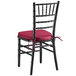 A Lancaster Table & Seating black wood Chiavari chair with a wine red cushion.
