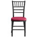 A black Lancaster Table & Seating Chiavari chair with a wine red cushion.