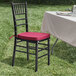 A Lancaster Table & Seating black wood Chiavari chair with a wine red cushion on a table.
