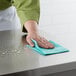 A hand cleaning a counter with a green Choice standard duty foodservice wiper.