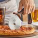 A person using a Mercer Culinary Millennia pizza cutter to cut a pizza.