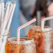 A close up of a glass of ice tea with a Choice red and white striped flex straw.