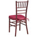 A Lancaster Table & Seating mahogany chiavari chair with a wine red cushion.