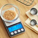 An AvaWeigh digital portion scale with a bowl of brown sugar on it.