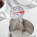 A CDN ProAccurate Insta-Read frothing thermometer in a metal container with white liquid.