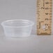 A clear plastic Dart Conex souffle cup next to a ruler.