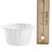 A Solo white paper souffle cup next to a ruler.
