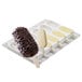 A chocolate covered ice cream bar on a white and yellow popsicle tray.