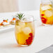 A Acopa Covella highball glass of ice tea with berries and a sprig of rosemary.
