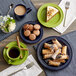 A table with a green Acopa Capri bamboo stoneware plate with cake and a mug of coffee.